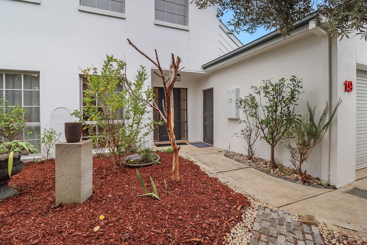A courtyard with a small tree, a concrete planter, and a building with a number 19 sign.