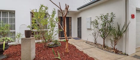 Un pati interior amb un arbre petit, una jardineria de formigó i un edifici amb el número 19.