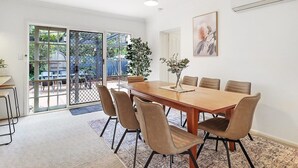 Un comedor con una mesa de madera y seis sillas, una planta en maceta y un cuadro en la pared.