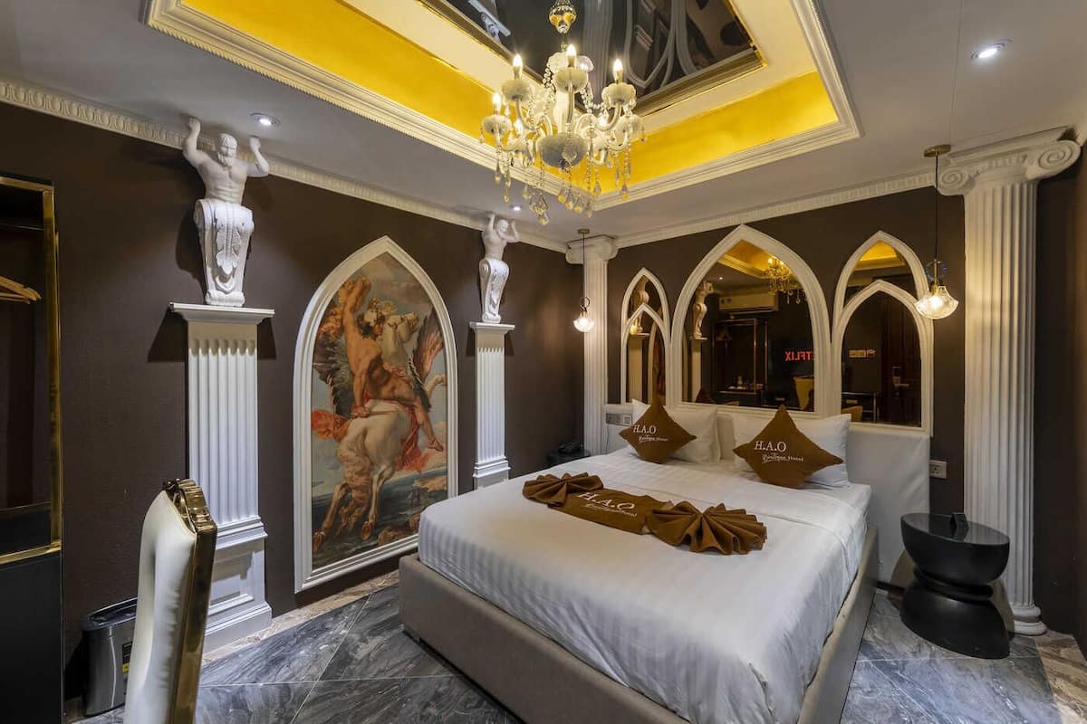 A luxurious bedroom with a large bed, ornate ceiling, and classical artwork.