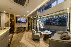A modern hotel lobby with a marble floor, a television, a bar area, and seating with a view of the outside. - H.A.O Boutique Hotel (Ho Chi Minh City)