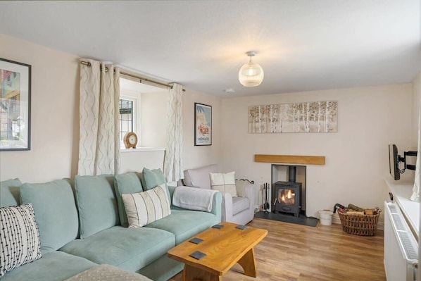 A cozy living room with a sofa, a wooden coffee table, a fireplace, and a hanging light fixture.
