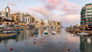 A waterfront cityscape with buildings, boats, and a calm river. - Remarkable 2-bed Apartment in St Julians (St. Julian's)