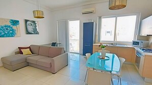 A modern apartment with a living area, dining space, and kitchen. It features a sofa, a glass dining table, and a kitchen with a microwave. - Remarkable 2-bed Apartment in St Julians (St. Julian's)