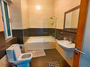 Une salle de bain moderne équipée d’une baignoire, de toilettes et d’un lavabo.