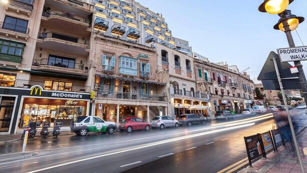 A multi-story building with a McDonald's on the ground floor, various shops on the ground floor, and a pedestrian walkway on the right. - Remarkable 2-bed Apartment in St Julians (St. Julian's)