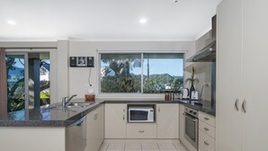A modern kitchen with a large window, built-in appliances, and a view of the outdoors.