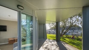 A modern interior with a large sliding glass door leading to a covered outdoor area with a view of a marina and boats.