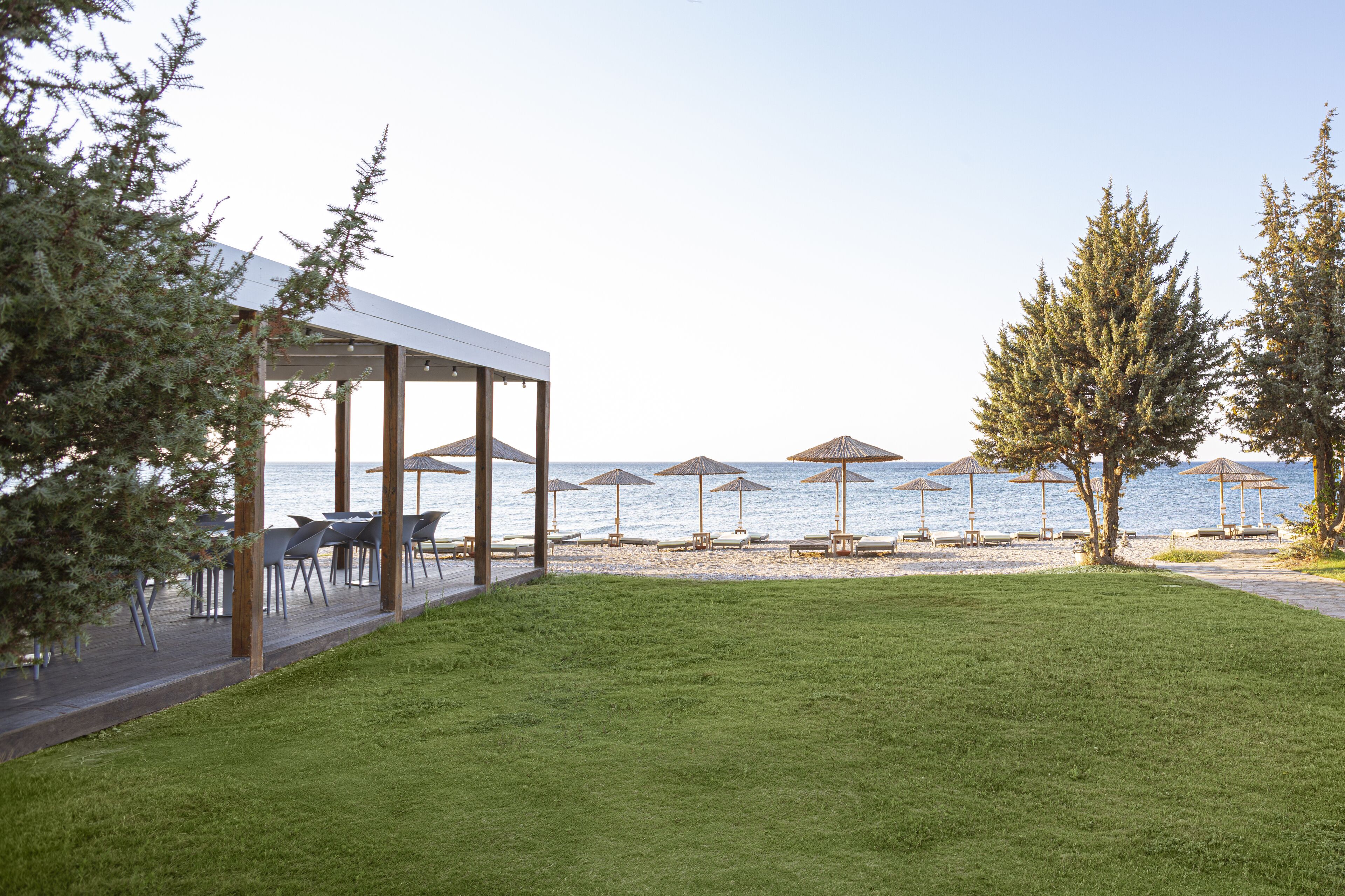 Una terrazza fronte mare con posti a sedere all'aperto e ombrelloni, con vista sul mare.