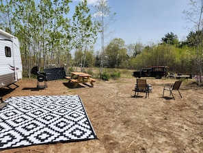 A campsite with a picnic table, chairs, a covered grill, and a caravan. - Week discount. RV on 365 ac parcel with 15 Mile Stream running thru the property (Albion)
