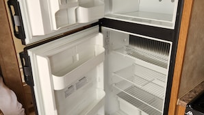 A modern kitchen with a built-in refrigerator, wooden cabinets, and a tiled backsplash.