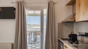 A kitchen with a view to the outside, a dining area with chairs, and a coffee machine. - Vagia Calm House 2 (Paros)