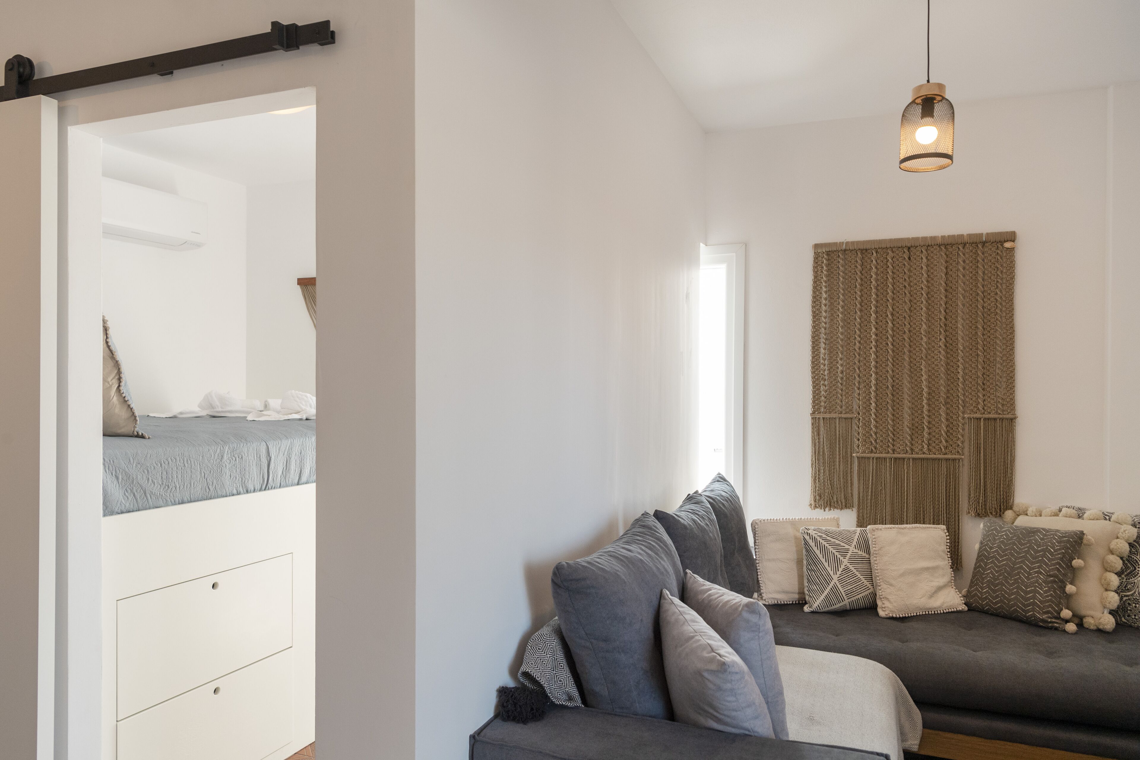 A modern bedroom with a bed, a sofa, and a large mirror.