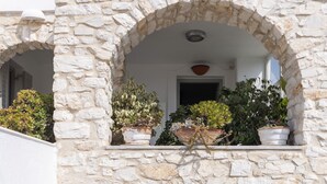 A stone building with an arched window and potted plants. - Vagia Calm House 2 (Paros)
