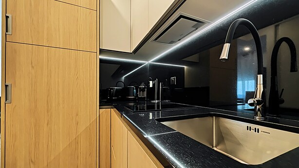 Een moderne keuken met houten kastjes, een zwart aanrecht en roestvrijstalen apparatuur.