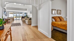 A spacious living area with a wooden floor, a dining table, and a sofa.