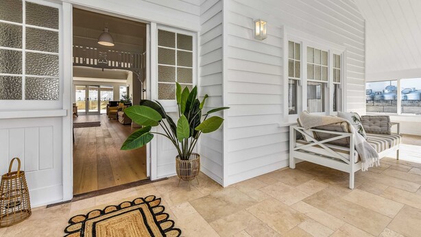 A spacious room with a large window, a white sofa, and a potted plant.