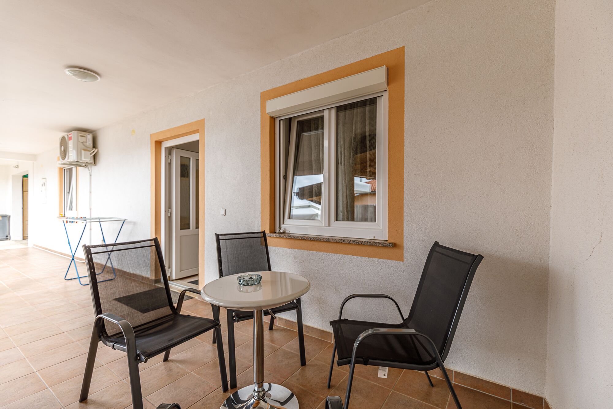 A room with a round table and four chairs, a window with curtains, and a ceiling fan.