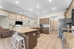 A modern kitchen with granite countertops, stainless steel appliances, and a central island.