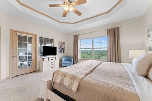 A hotel room with a bed, a TV, a desk, a chair, and a window with a view.