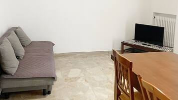 Una habitación con cama, una mesa de comedor y un televisor. Hay tres cuadros en la pared.