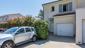 A residential area with a white car parked in front of a house with a garage. - Cibelle - Charmante maison avec terrasse (Cers)