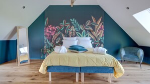 A bedroom with a bed, pillows, and a large floral mural on the wall. - Un nid dans la Grange - Maison avec jacuzzi et sauna (Boué)