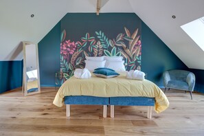 A bedroom with a bed, pillows, and a large floral mural on the wall.