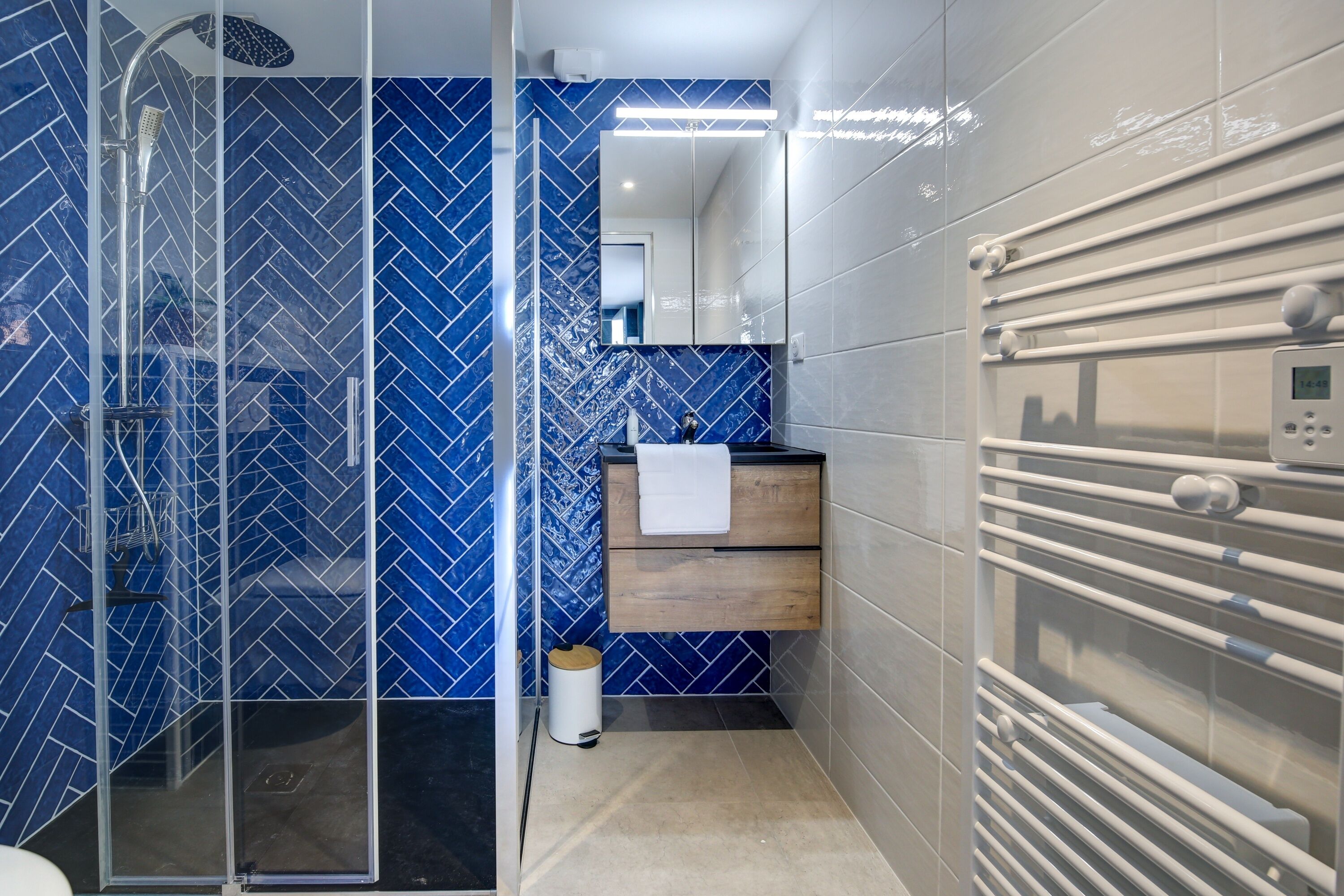 Een moderne badkamer met een douchecabine van glas, een houten wastafelmeubel en een ingebouwde verwarming.