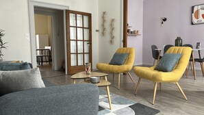 Un salon moderne avec deux fauteuils jaunes, un canapé gris et une table basse.
