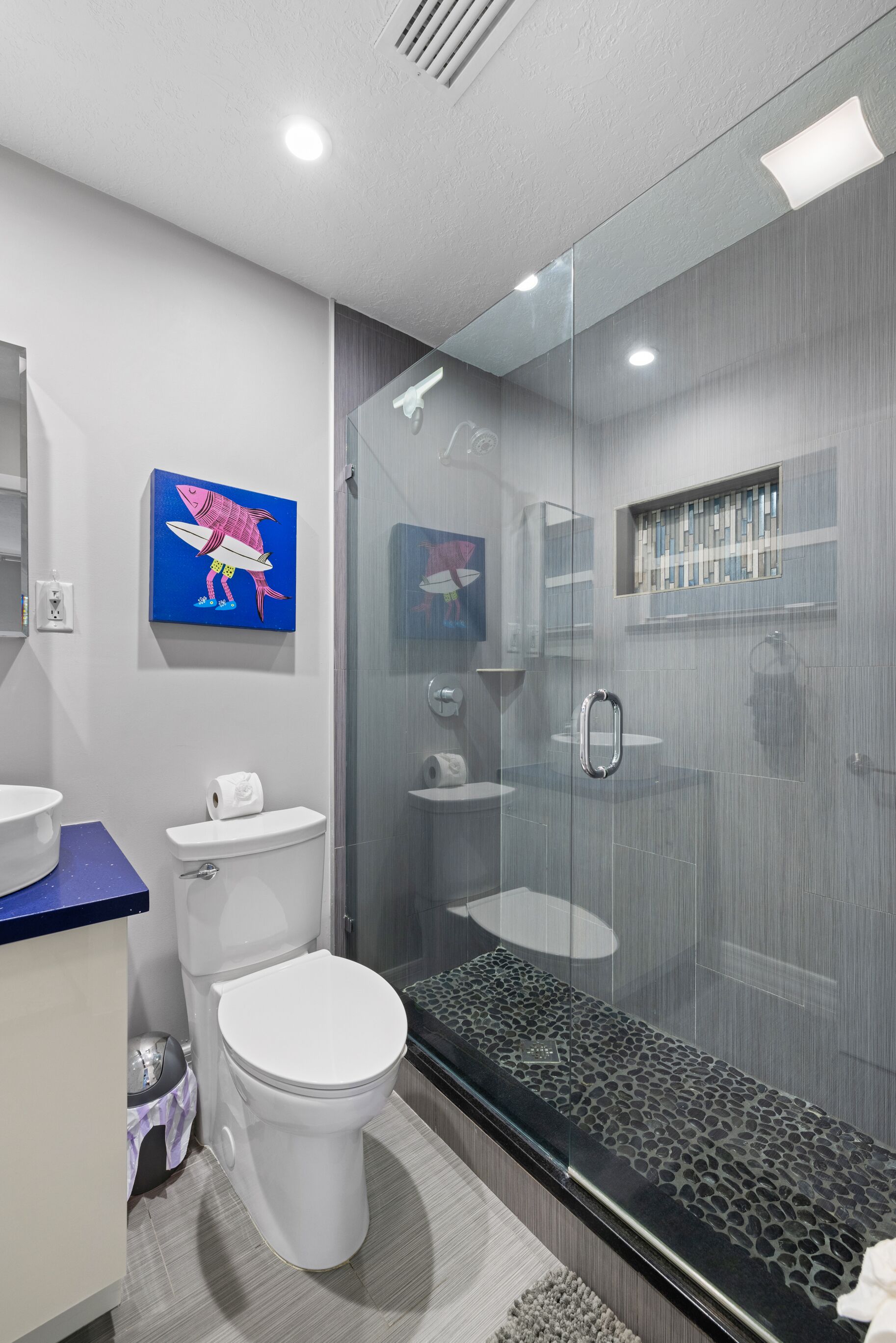 Un baño moderno con cabina de ducha de vidrio, inodoro y lavamanos.