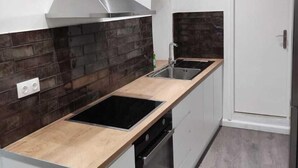 A modern kitchen with a stainless steel range hood, a double sink, and a built-in oven. - Saint's View Apartments (Corfu)
