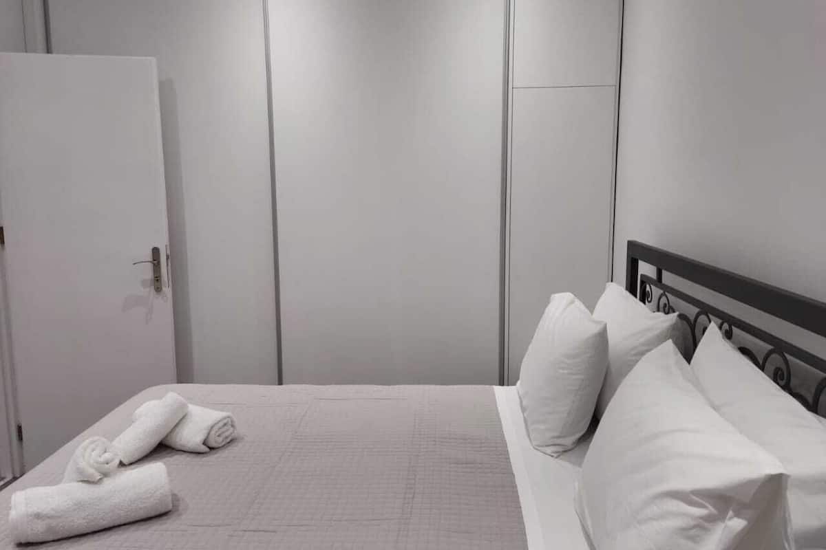 Ein Hotelzimmer mit einem Bett, Kissen und einem aufgerollten Handtuch auf dem Boden.