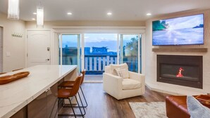 Ein modernes Wohnzimmer mit Kamin, einem an der Wand befestigten Fernseher und einem Balkon mit Blick auf die Stadt.