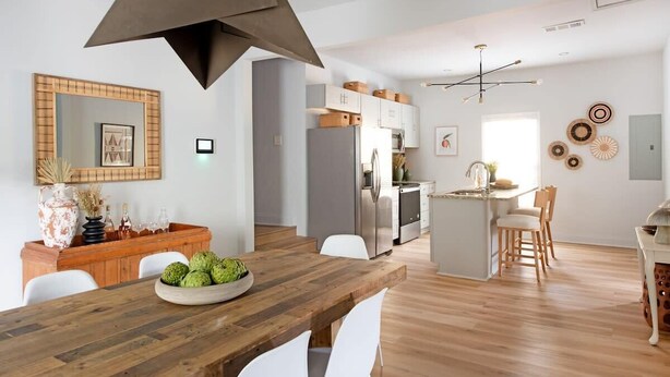 A modern kitchen with a central island, white cabinetry, and a wooden dining table with chairs. - Scandi Candi (Atlanta)