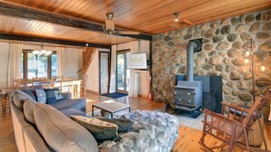 A cozy living room with a stone wall, a fireplace, a sofa, and a rocking chair.