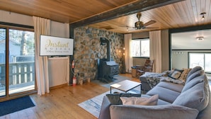 A cozy living room with a stone wall, a fireplace, a sofa, and a television displaying "Instant Suites."