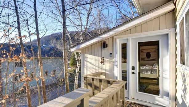 A wooden deck with a white door leading to a room with a bed and a fireplace.