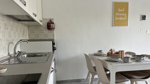 Een moderne keuken met een inbouwoven, een spoelbak en een eethoek met een tafel gedekt voor twee personen.