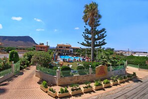 A hotel with a swimming pool, surrounded by greenery and a mountain in the background. - Despo Hotel by Estia (Hersonissos)