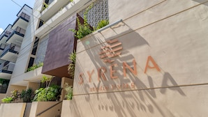 La façade d’un immeuble porte l’inscription « SYRENA studio living », et un escalier y mène à un étage supérieur.