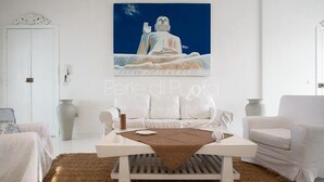 A modern living room with a white sofa, a coffee table, and a large Buddha statue painting on the wall. - 3361 Attico Barca by Barbarhouse (Gallipoli)