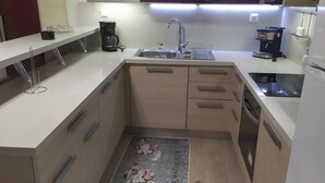 A compact kitchen with a sink, coffee maker, and a small refrigerator.