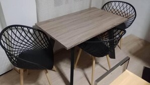 A small dining area with a wooden table and two black wireframe chairs.