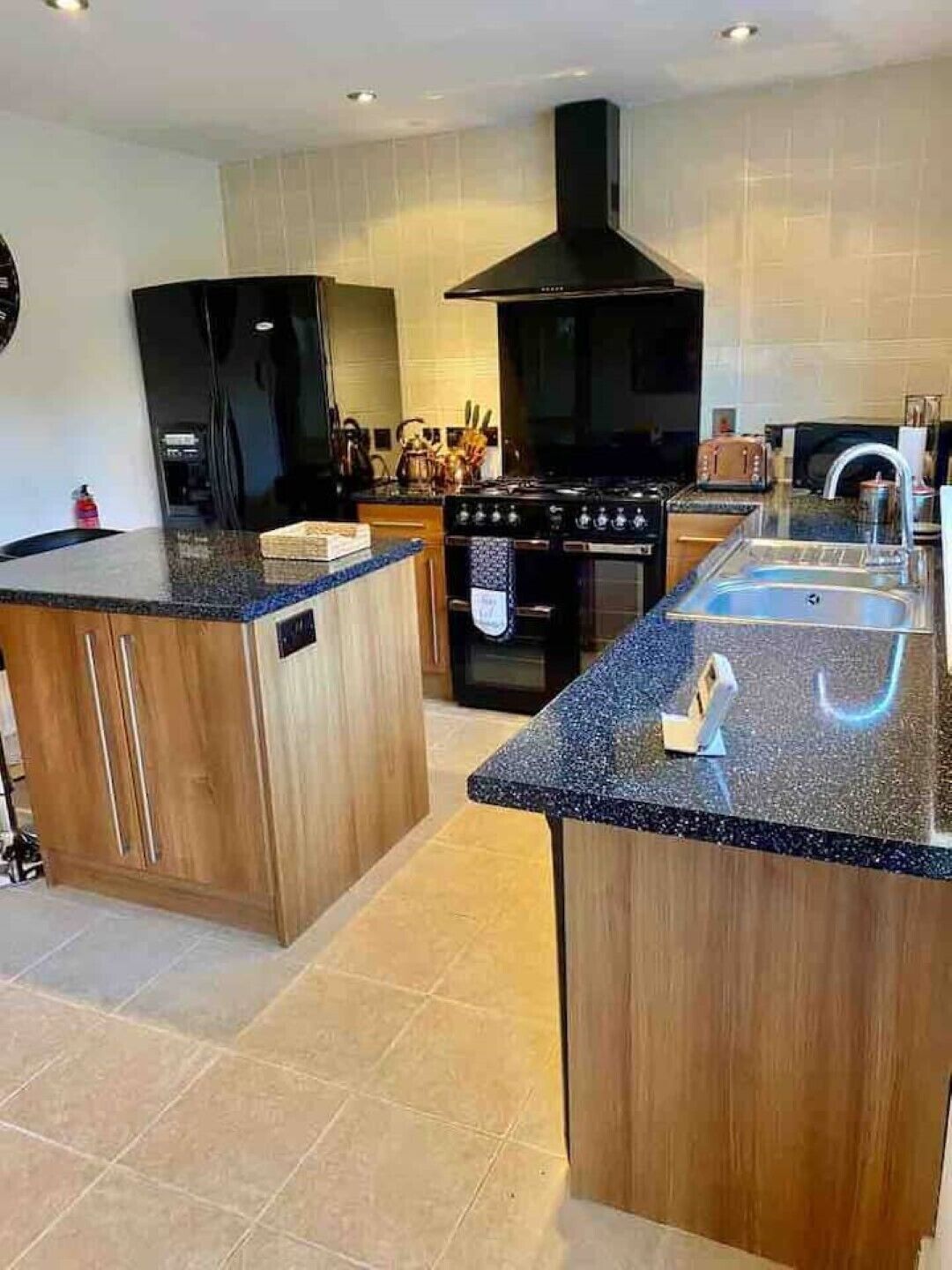 A modern kitchen with a central island, a stove, and a black range hood.