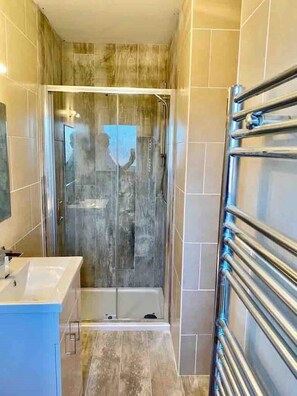 A modern bathroom with a glass-enclosed shower, a white sink, and a towel rack. - Beautiful 4 bedroom Townhouse close to Belfast city centre and the Ormeau Park. (Belfast)