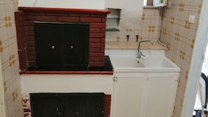 Uma cozinha compacta com forno de tijolos embutido, pia e paredes revestidas de azulejos.
