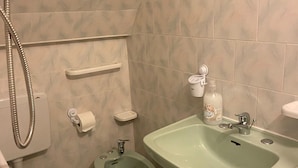 Casa de banho com sanita, bidé, lavatório e chuveiro.