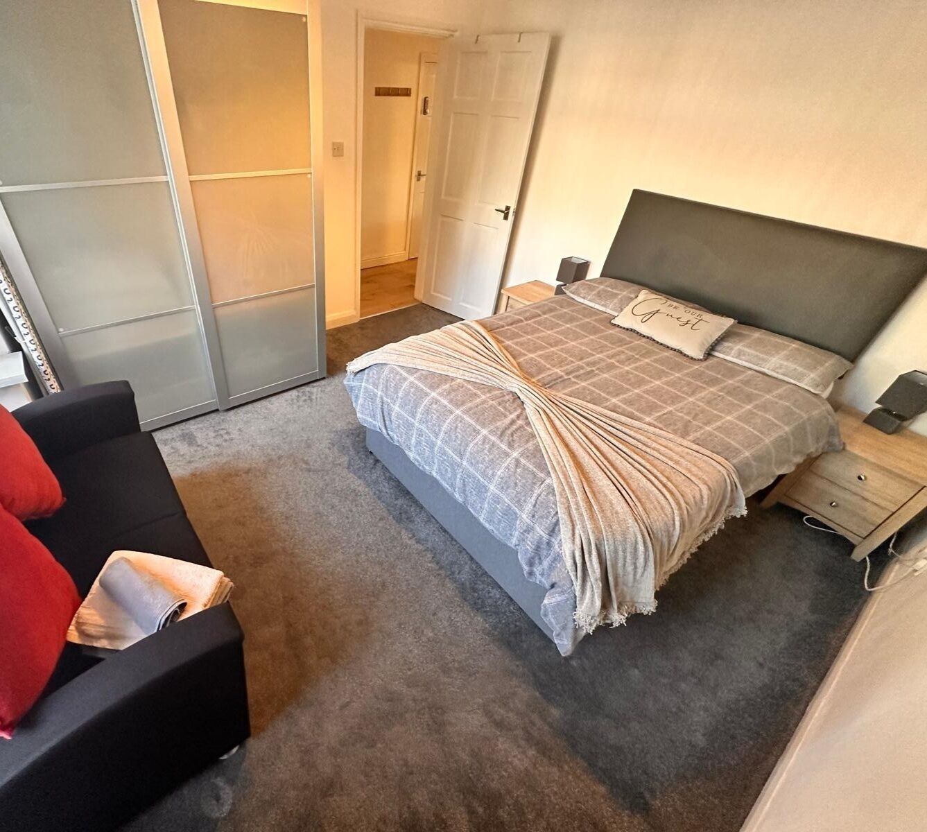 A bedroom with a bed, a nightstand, a chair, and a wardrobe.