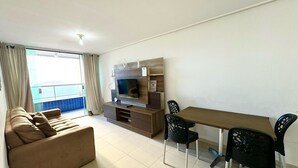 Una sala de estar moderna con sofá, televisor, mueble de televisión de madera, mesa de comedor y sillas.